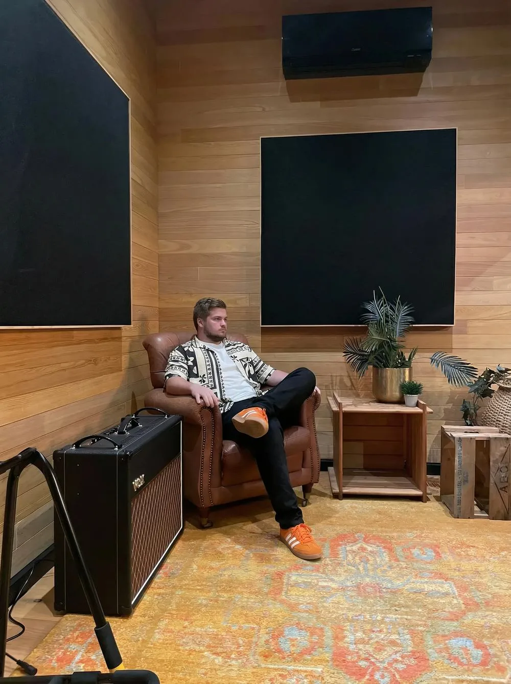 Ben in an armchair in the live room, a guitar amp beside him